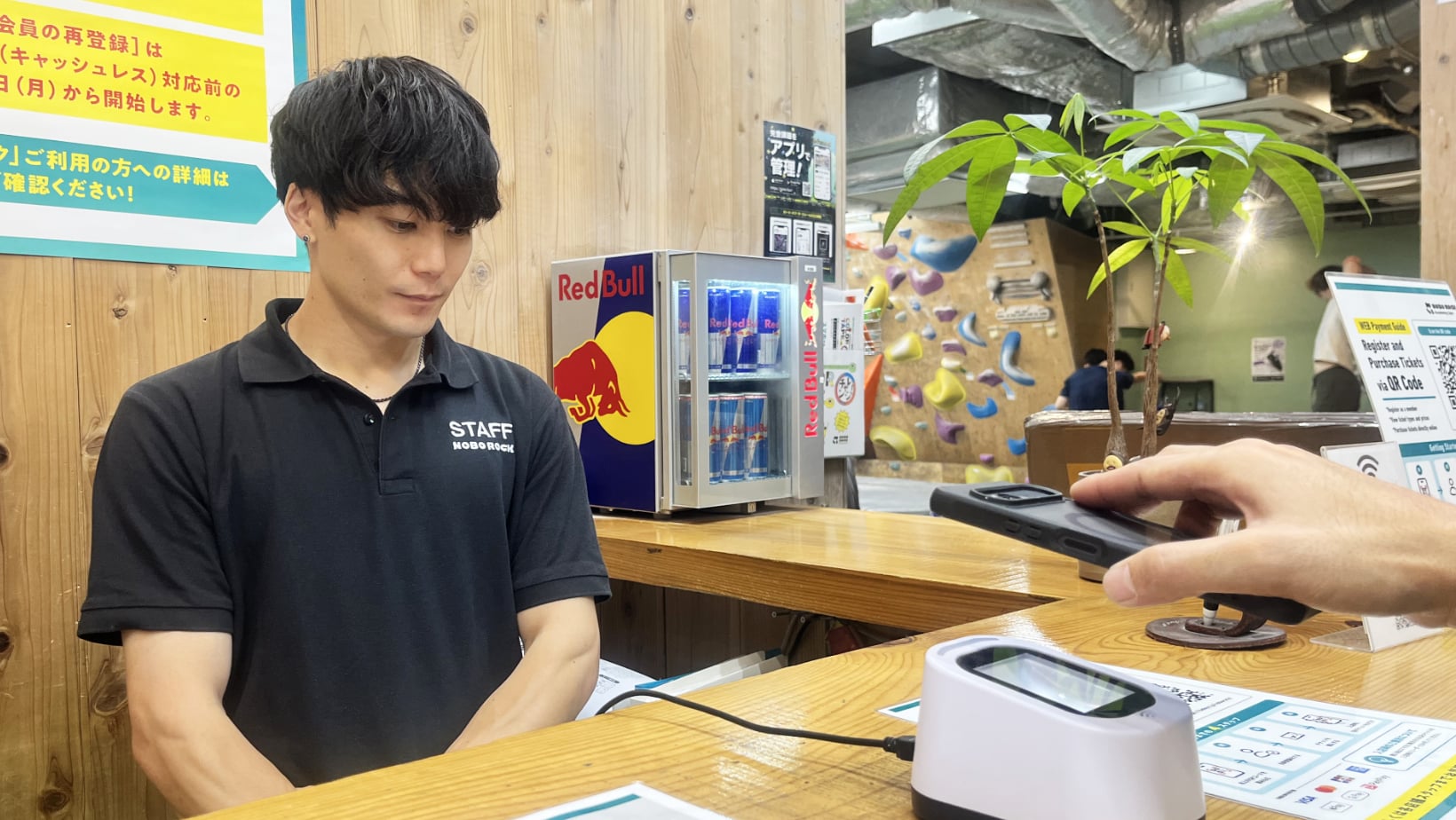 受付カウンターで、お客様がスマートフォンの画面をQRリーダーにかざしている様子